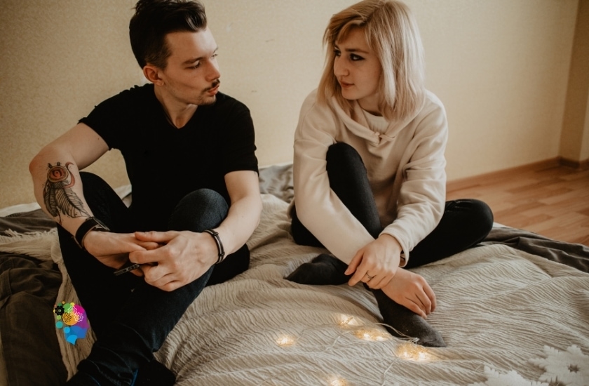  a couple on a bed, with one partner talking and the other listening attentively in a post about how to be a better girlfriend