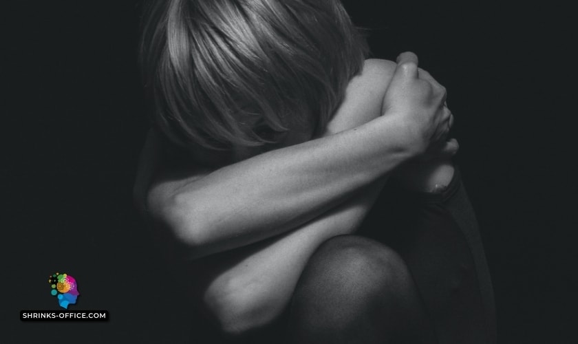 A grayscale photo of an individual hugging their knees close, conveying a moment of solitude and contemplation, symbolizing the theme of how to overcome self-hatred and build self-love.